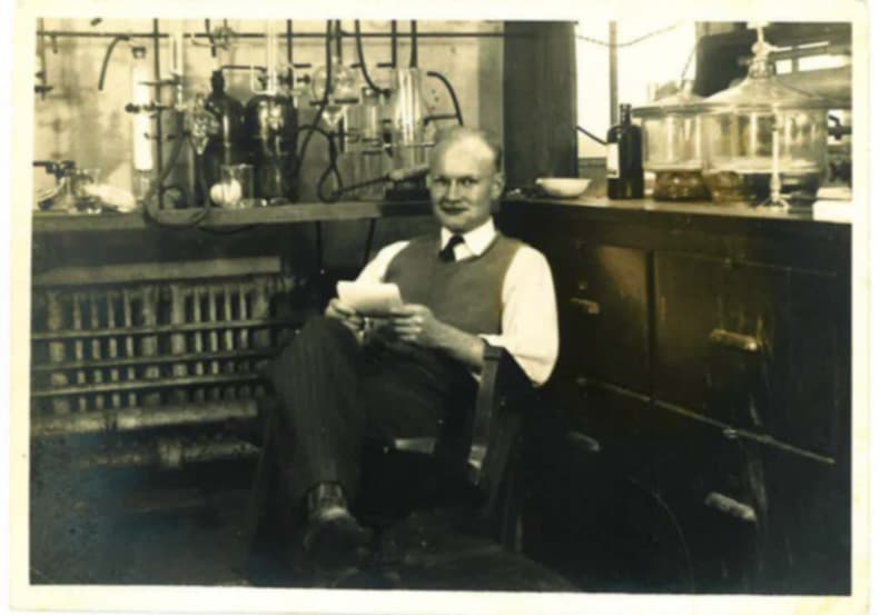 Black-and-white photograph of Cecil M. Knowles seated in a chemistry laboratory surrounded by glassware