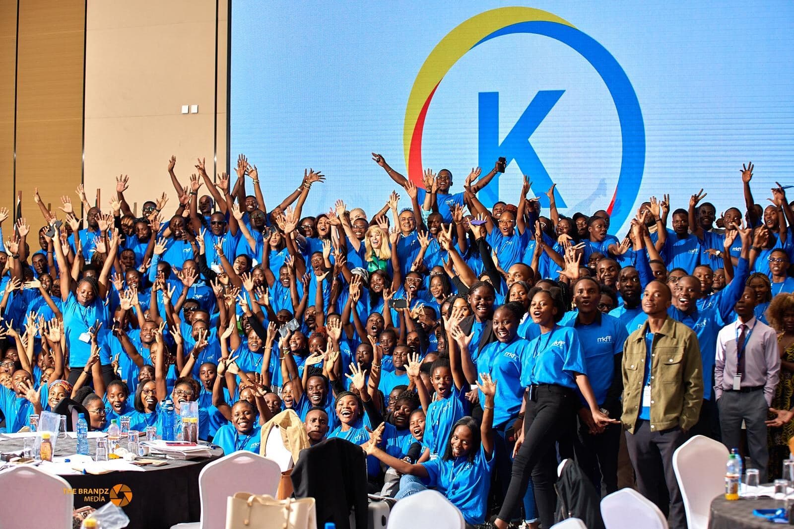 Large Kectil group cheering in front of the Kectil logo.